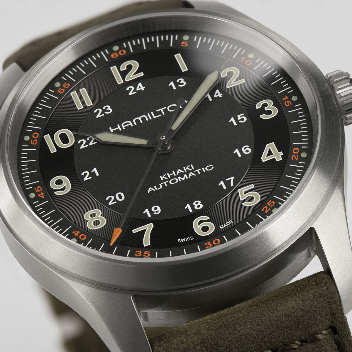 Hamilton Khaki Field H70205830 38mm watch close-up detail displaying black dial texture, luminous hands, and orange-tipped second hand