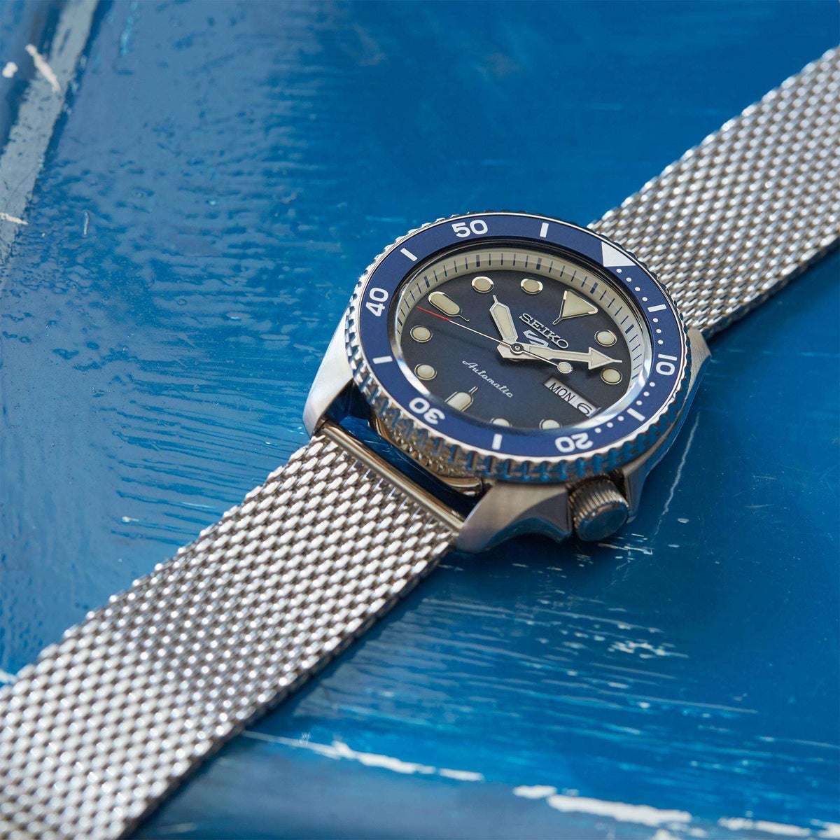 Blue-dial automatic men's watch with steel mesh bracelet and rotating bezel