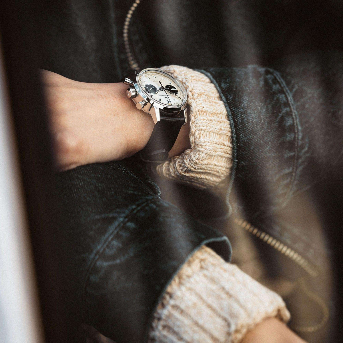 Hamilton chronograph watch on wrist with black leather strap and silver case on dark jacket