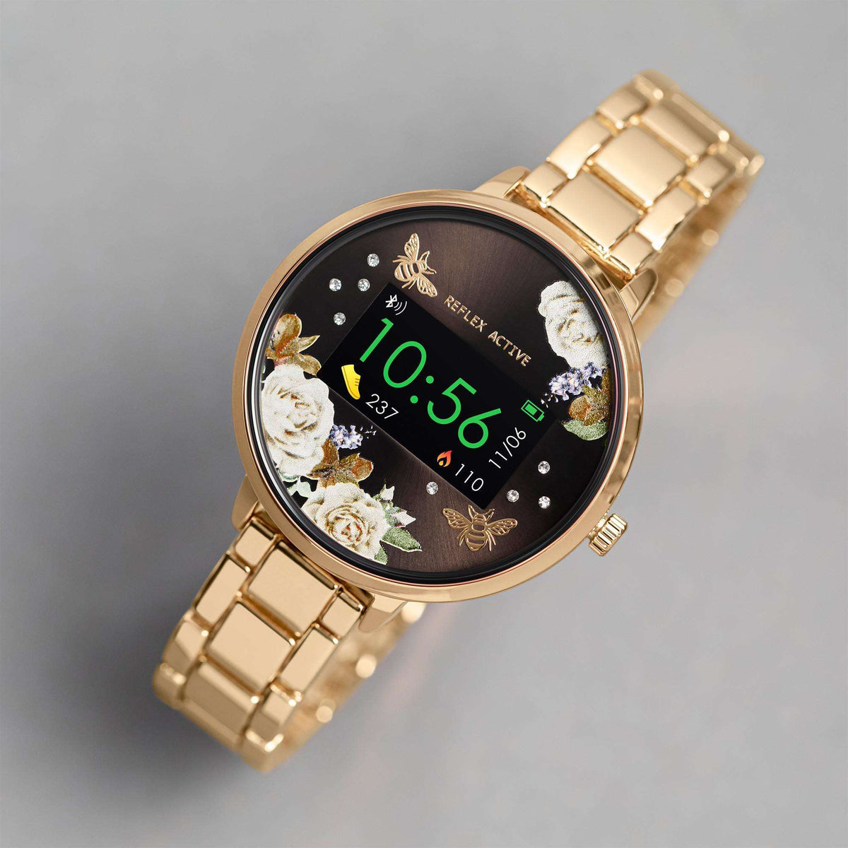 Gold bracelet smartwatch with angled view of black floral dial and digital time