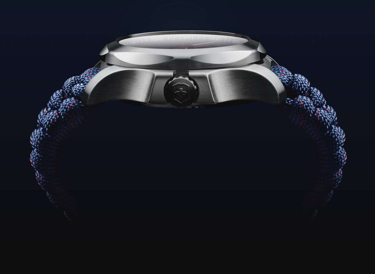 Silver watch case side view with crown and blue paracord strap knot detail.