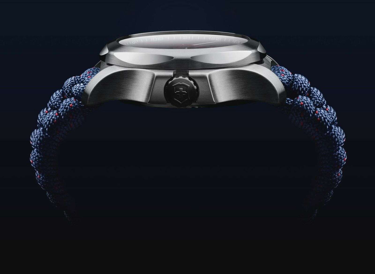 Silver watch case close-up with crown and blue paracord strap, front lugs visible.