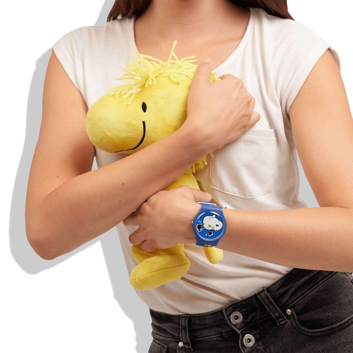 Blue Snoopy dial watch on wrist with white T-shirt and yellow plush toy