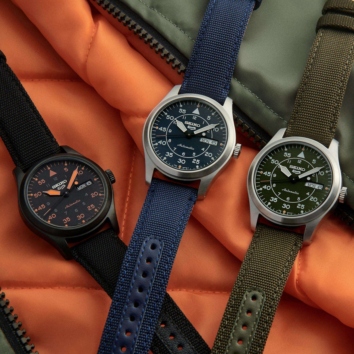 Men's automatic pilot watch with black-orange dial and black canvas strap, side view