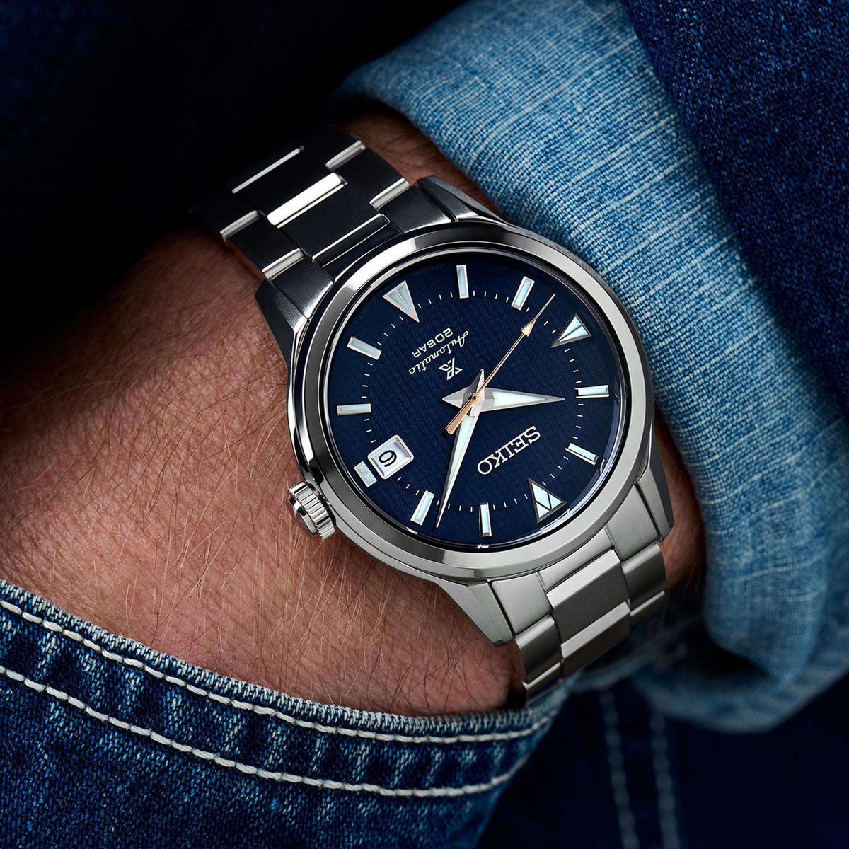 Men's stainless steel automatic watch on wrist, blue dial, metal bracelet, date window