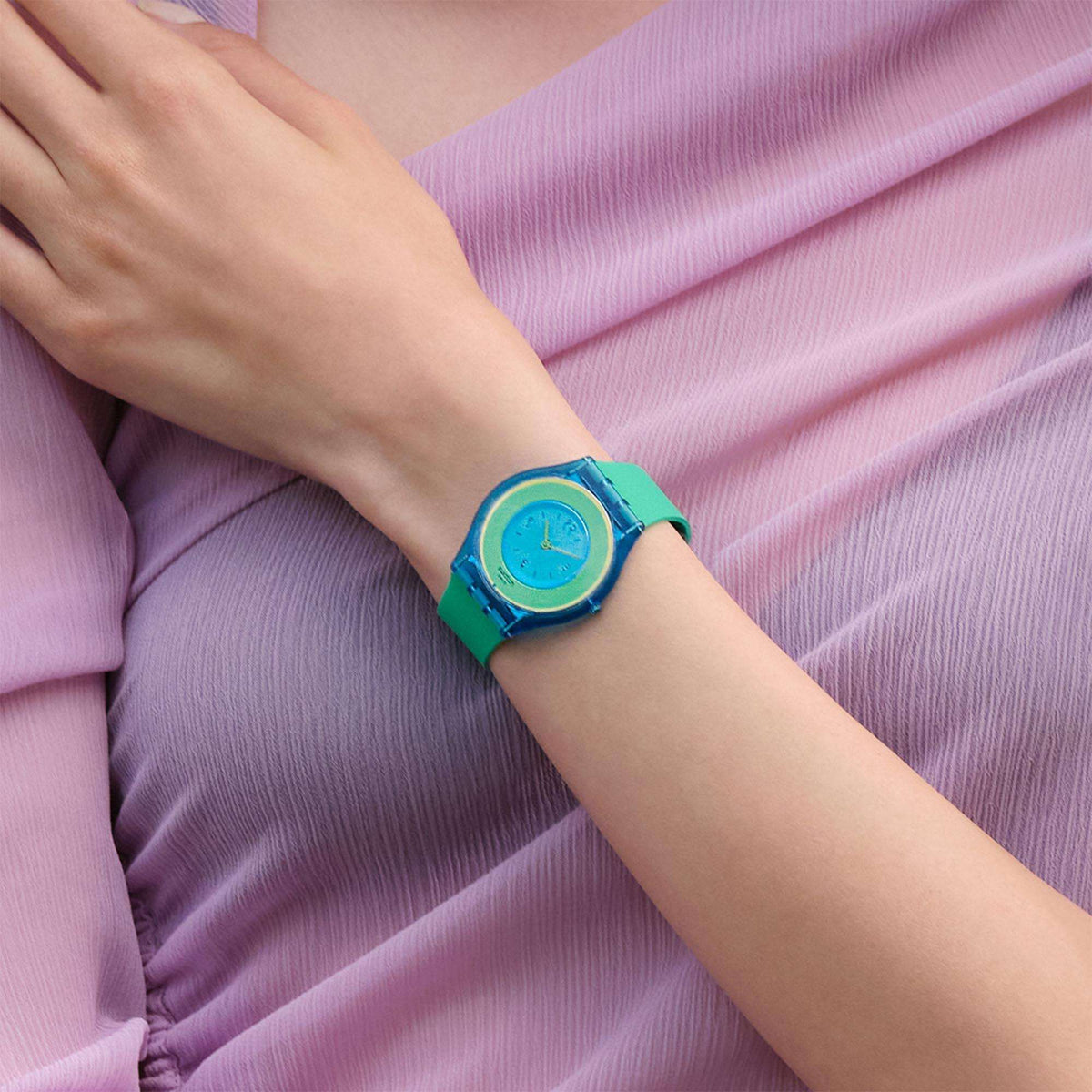 Unisex quartz watch worn on wrist, mint green silicone band with blue and yellow dial