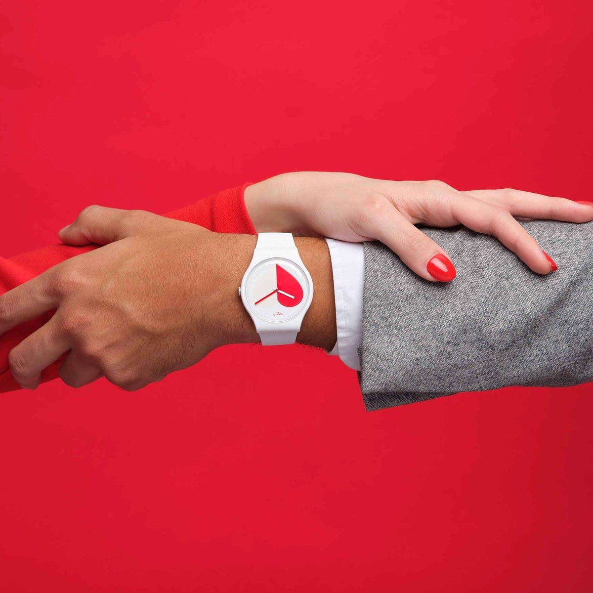 White silicone strap watch with red heart dial on wrist, overlaid with gray fabric