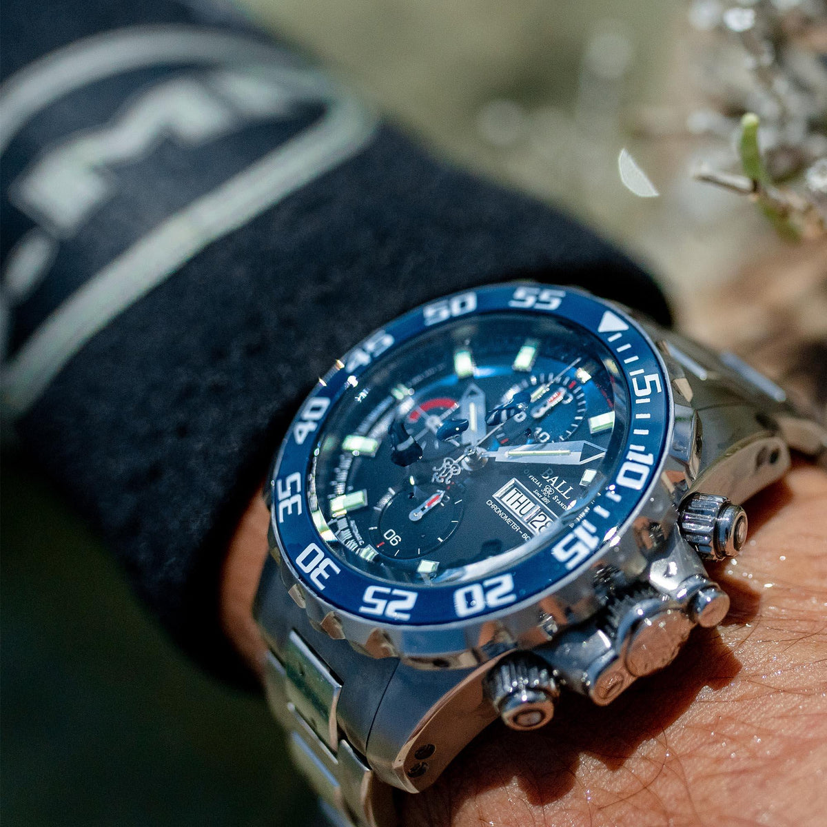 Men's steel chronograph watch with blue dial and luminous bezel markings on wrist