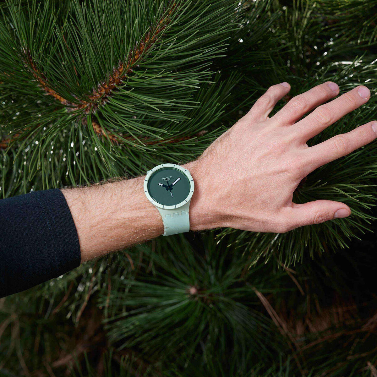 Round green dial silicone strap watch on wrist, light green strap and dark green face.