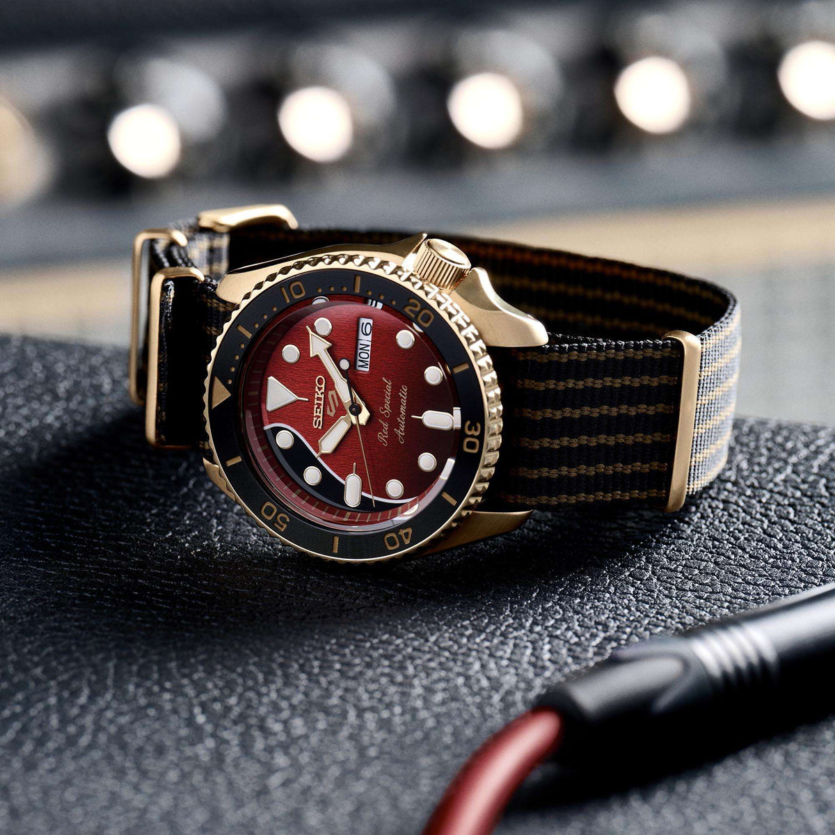 Men's automatic watch on dark fabric strap, red dial with gold markers and day window
