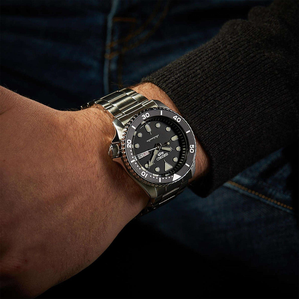 Men's Seiko 5 Sports automatic watch on wrist with black dial and silver stainless band