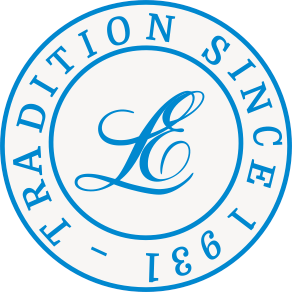 Blue circular emblem with script monogram on a white center, surrounded by ring text