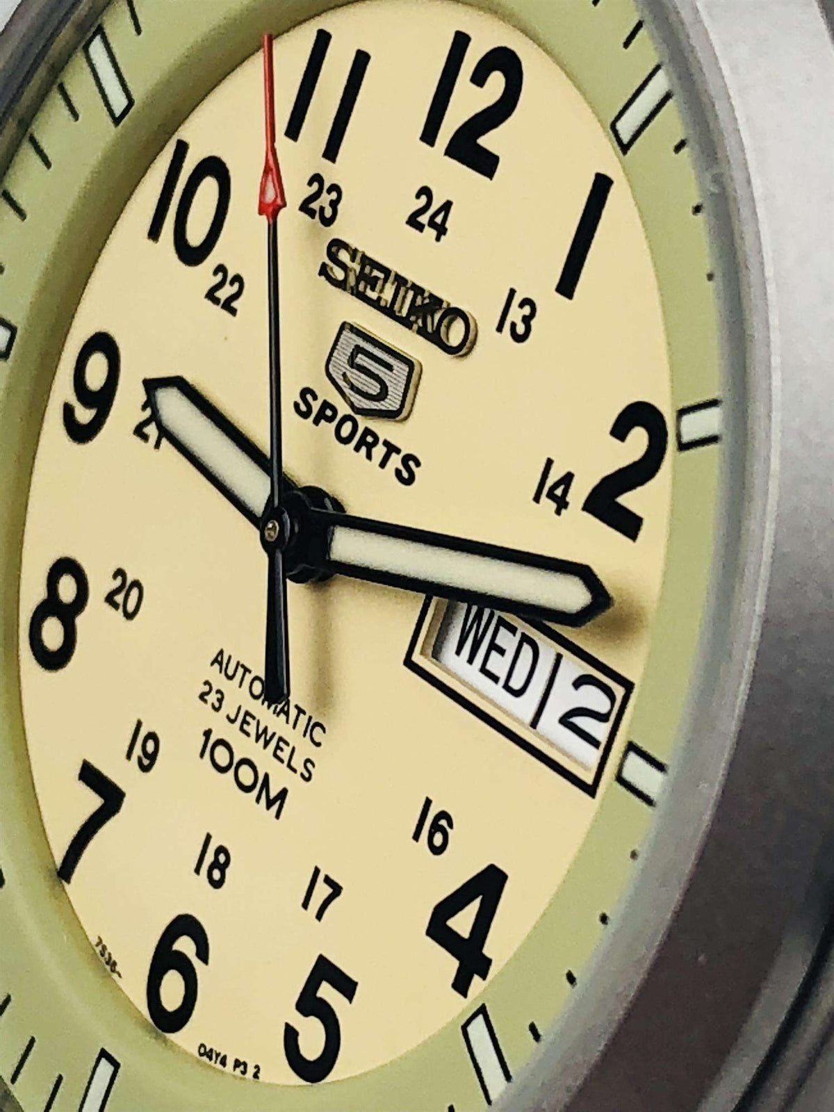 Close-up of cream dial sports watch with black hands and date window