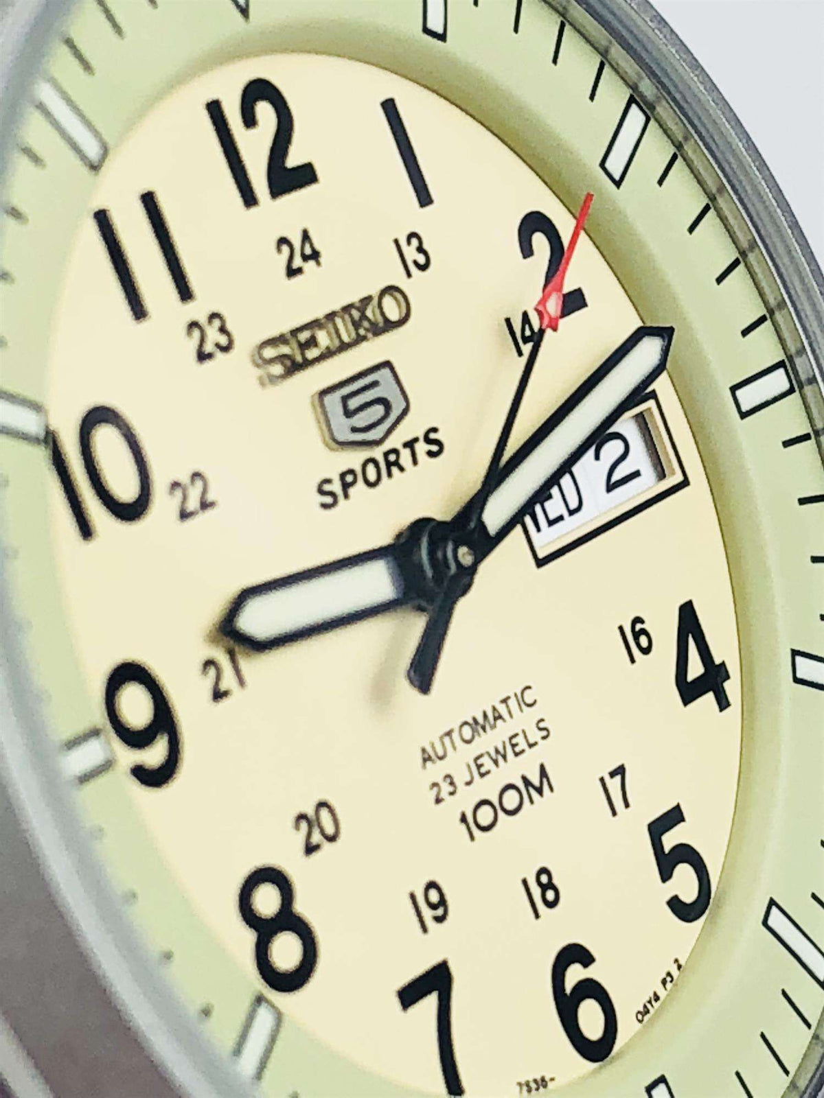 Extreme close-up of cream watch dial with black hands and date display
