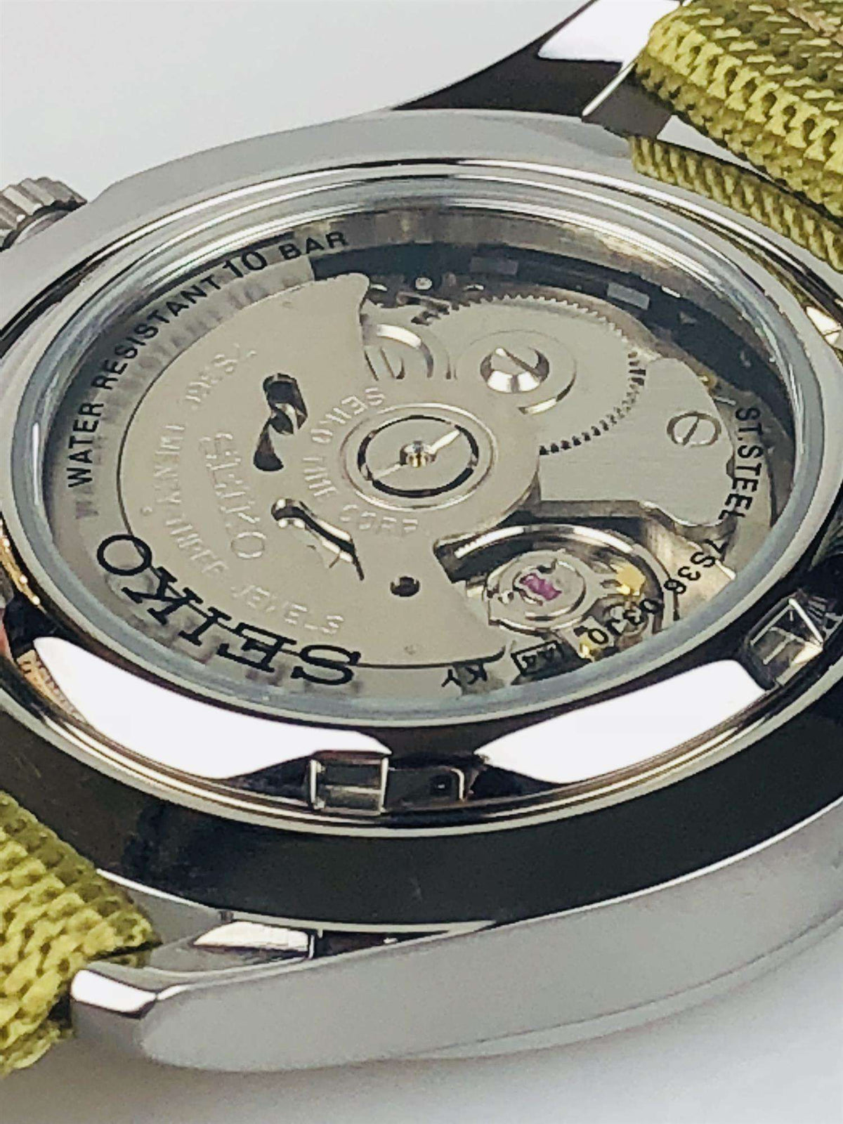 Stainless steel caseback of an automatic sports watch on olive canvas strap