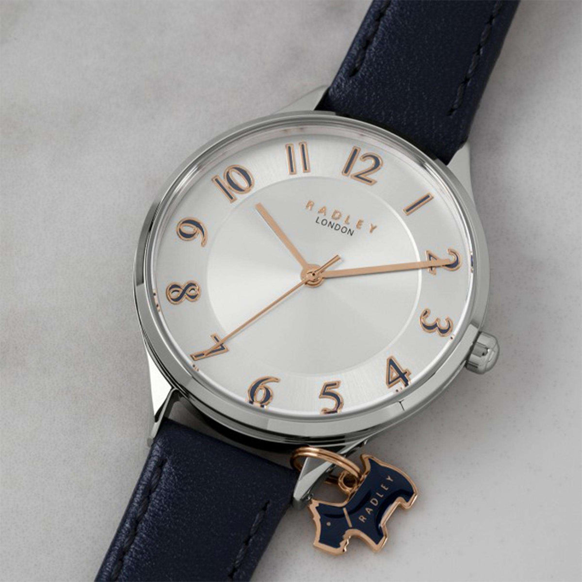 Ladies quartz watch close-up, white dial with gold markers, navy leather strap, horse charm