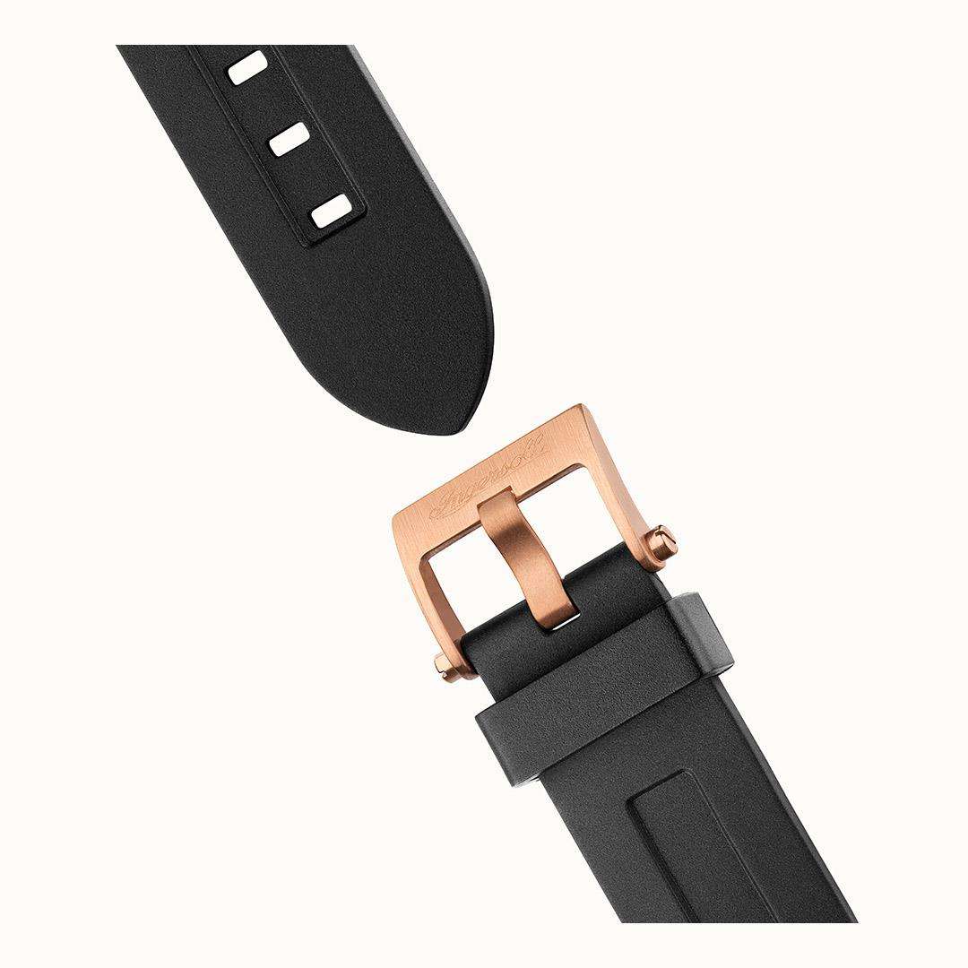 Black rubber watch strap with rose-gold buckle and clasp hardware.