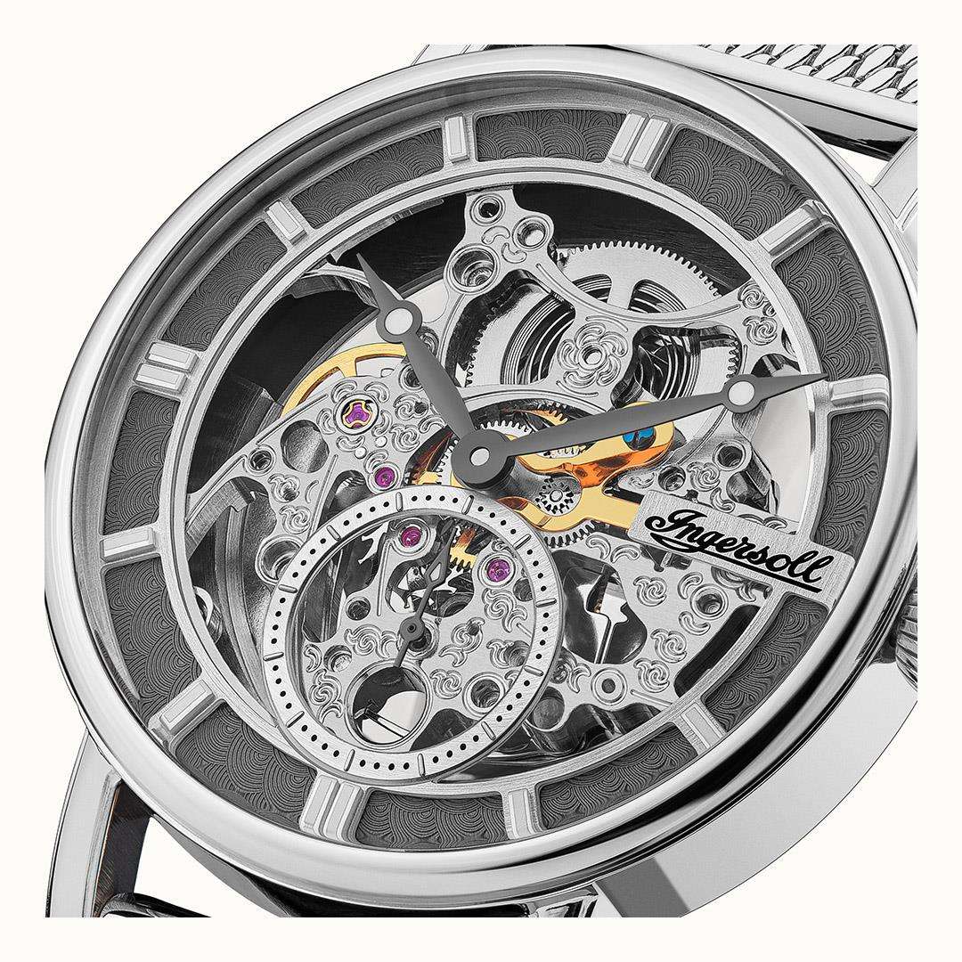 Close-up of men's automatic skeleton watch movement on grey dial, silver case.