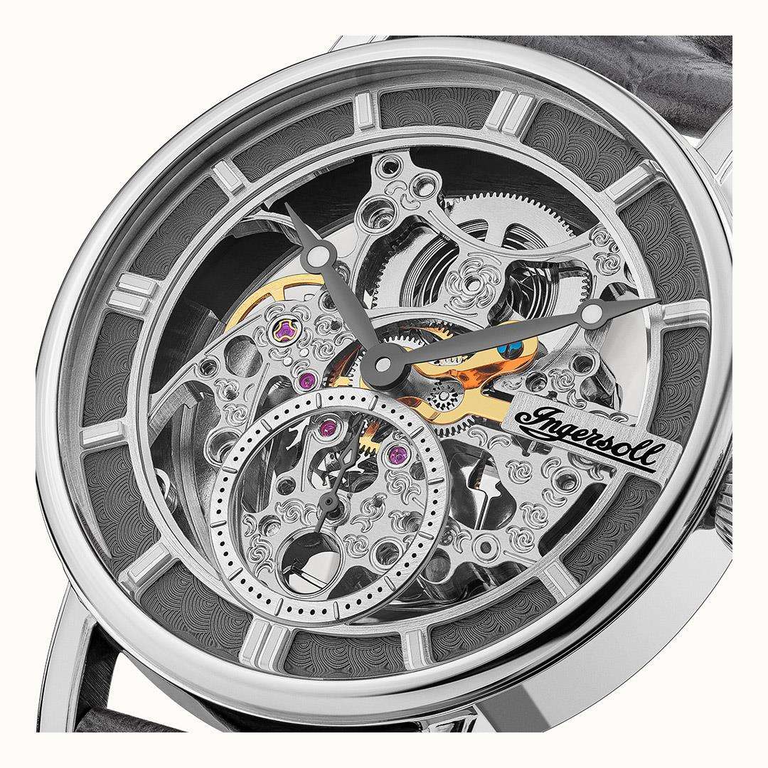 Close-up of transparent watch dial showing silver gears and orange accent hands