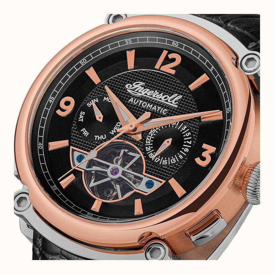 Men's automatic wristwatch dial close-up with skeleton movement, black face, rose-gold details.