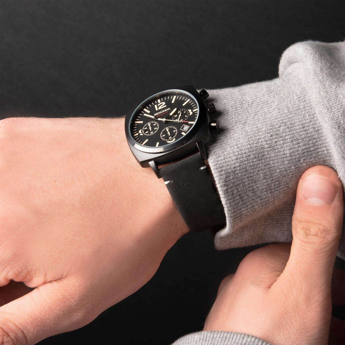 Men's wristwatch worn on black strap; black dial with subdials and gold-tone markers