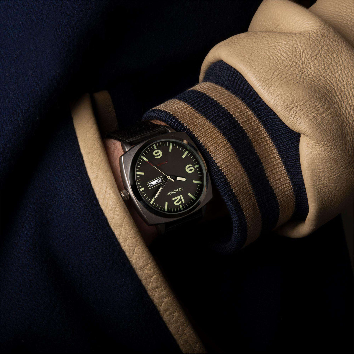 Men's quartz watch on wrist with black dial and black strap over striped sleeve