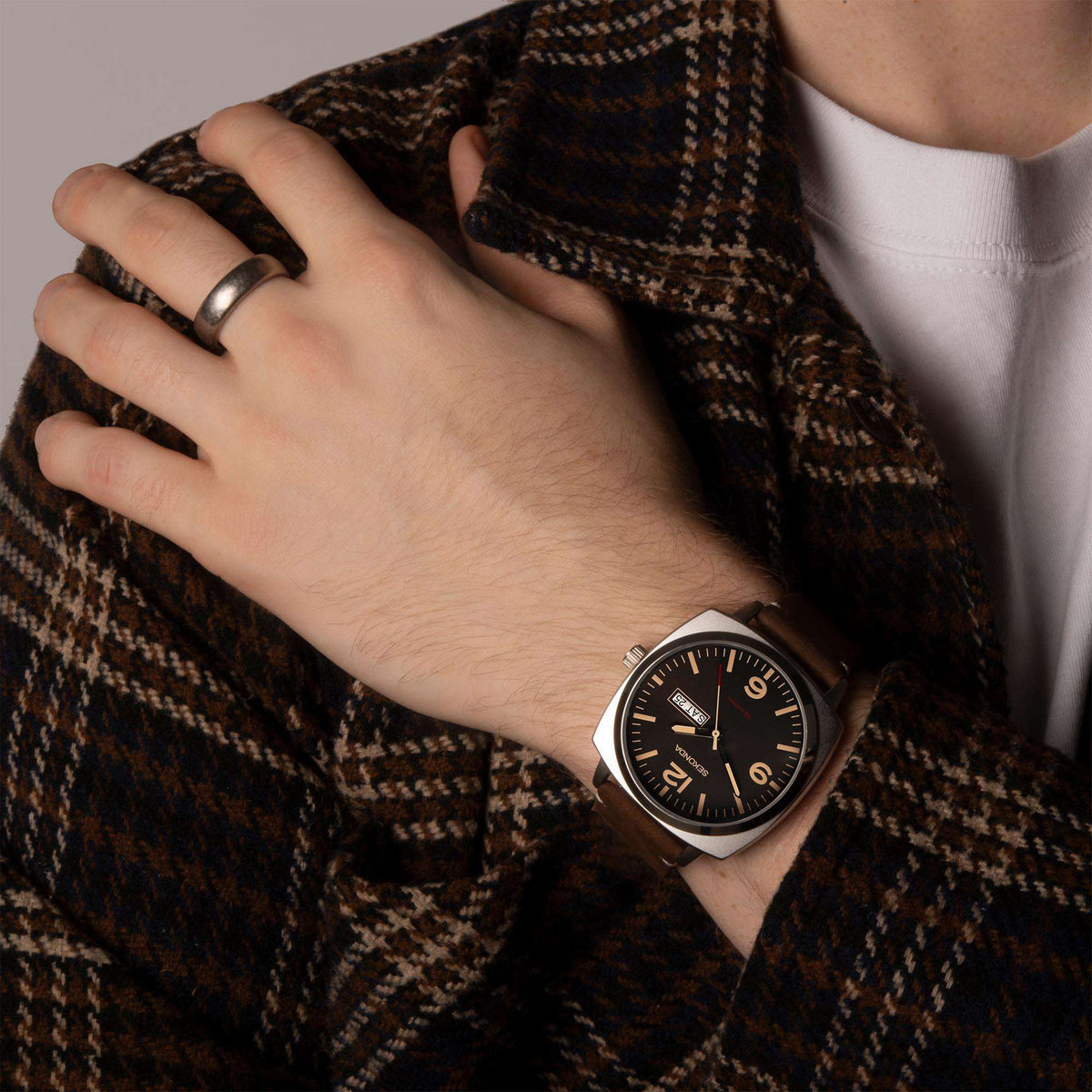 Men's quartz watch on wrist with black dial and brown leather strap