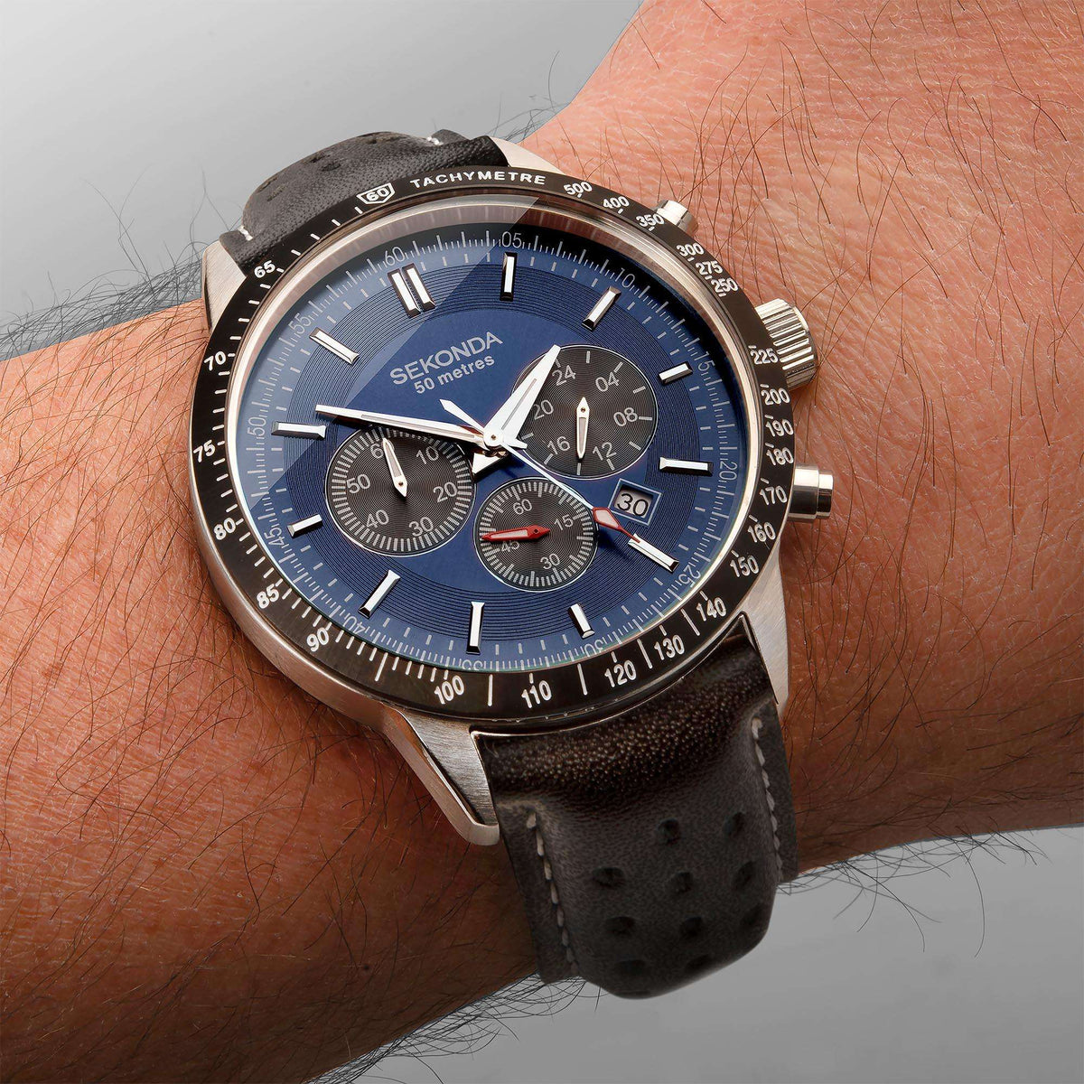 Men's chronograph watch on wrist with blue dial and black leather strap