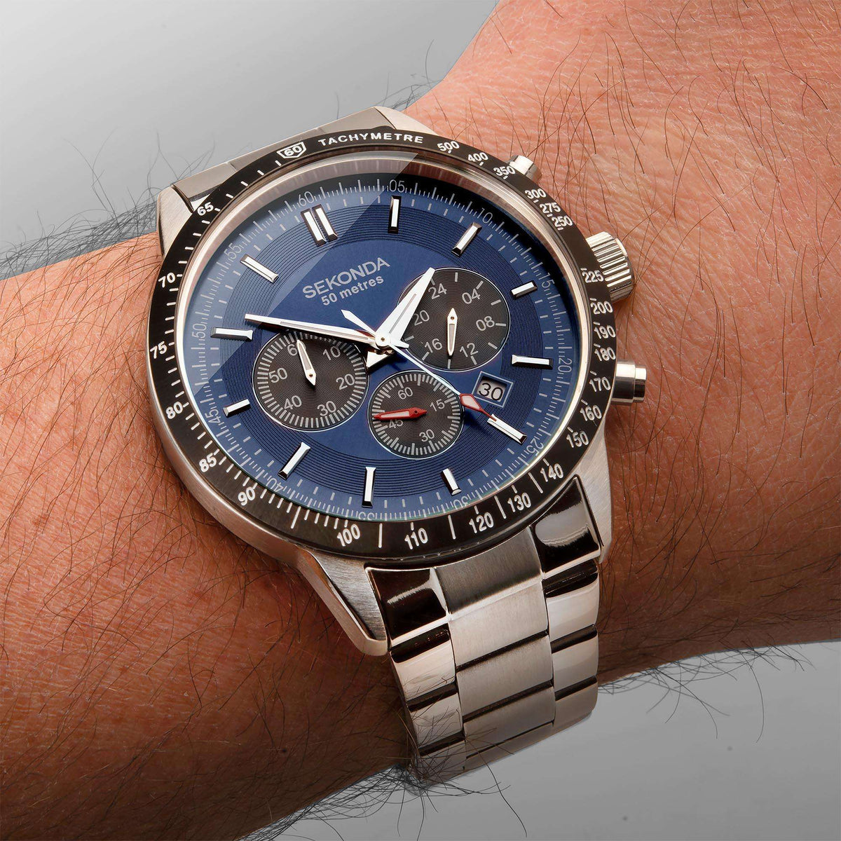 Men's stainless steel chronograph watch on wrist, blue dial with subdials and bracelet