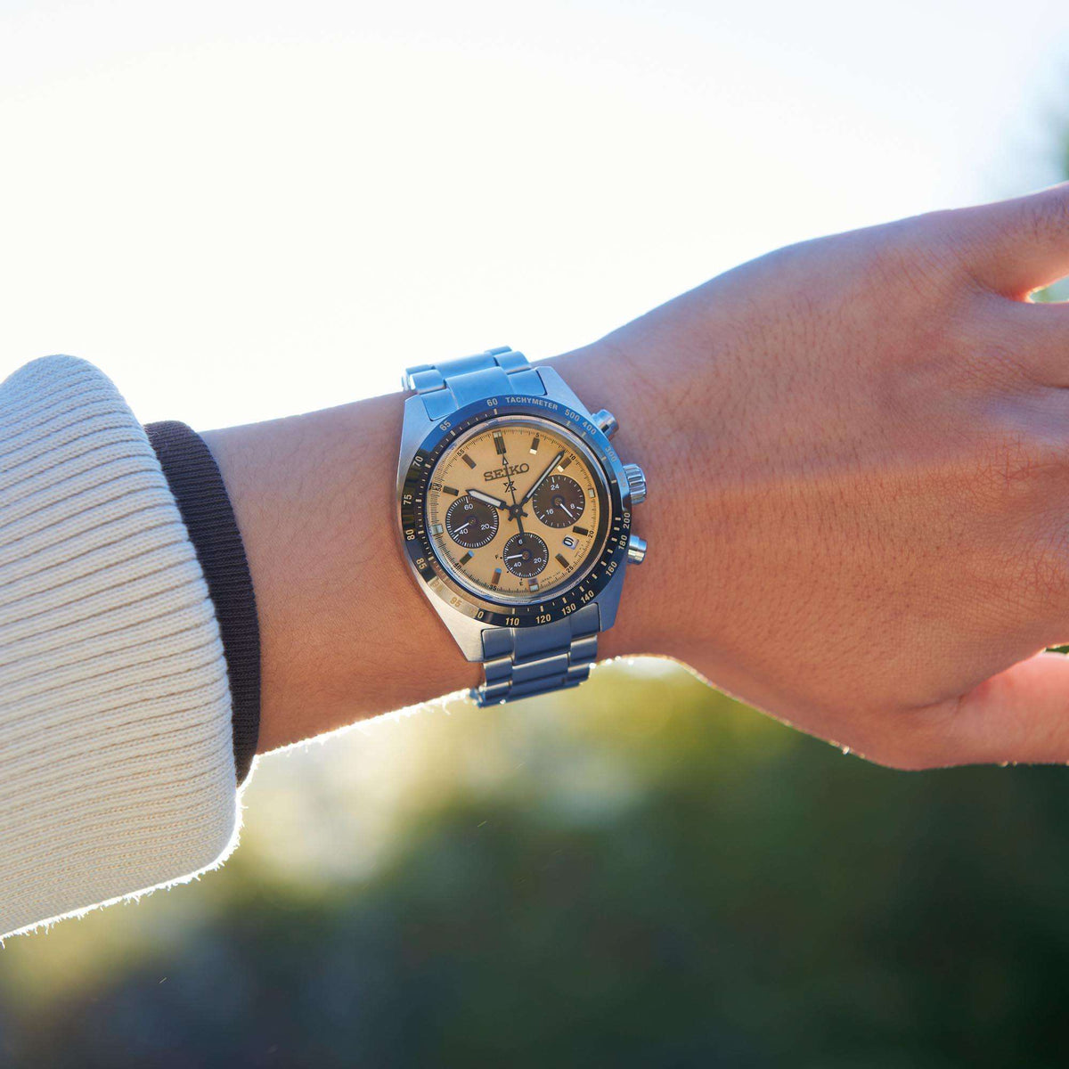 Seiko chronograph watch on wrist with gold dial, steel bracelet, tachymeter scale on bezel
