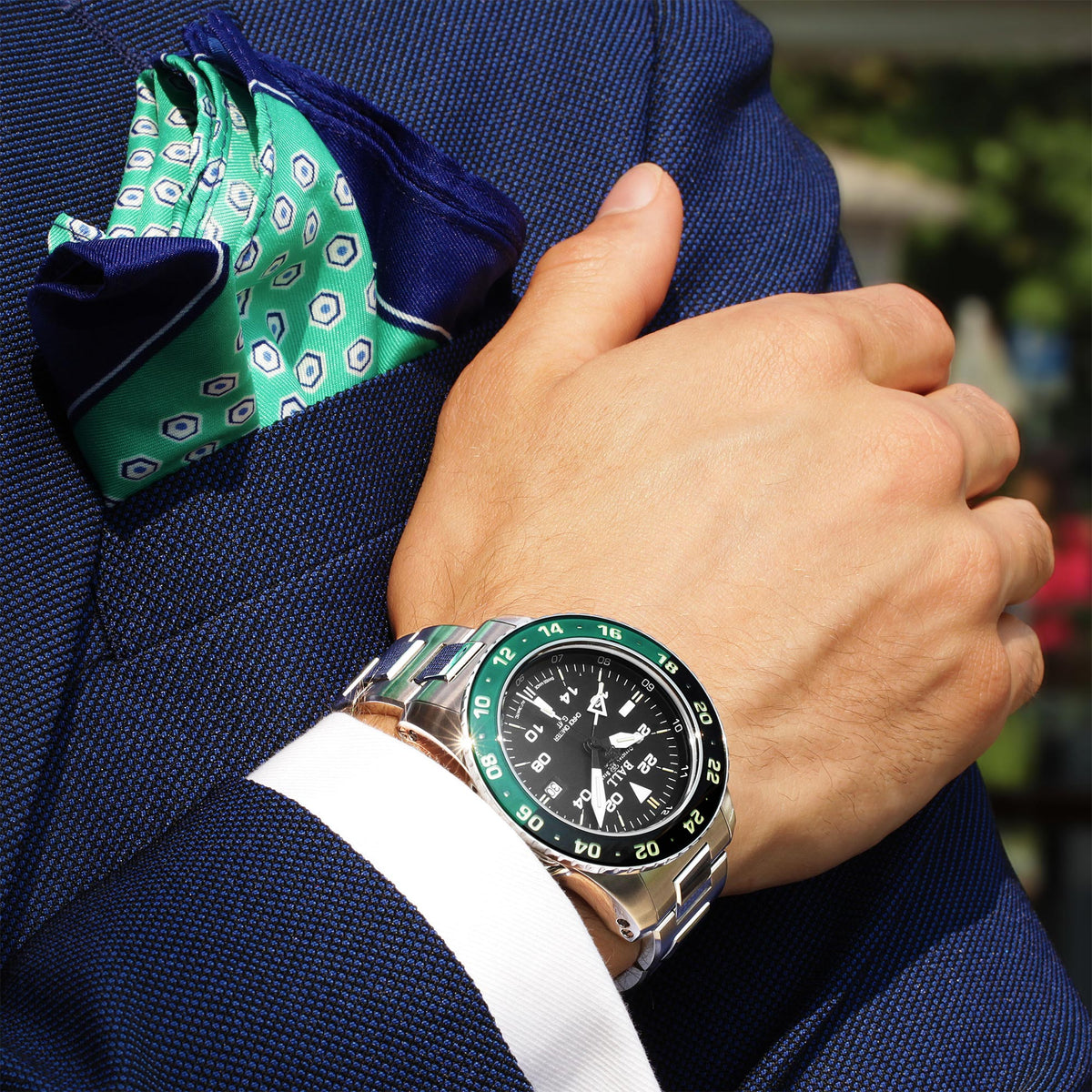 Men's automatic wristwatch on wrist, black dial, green bezel, steel link bracelet