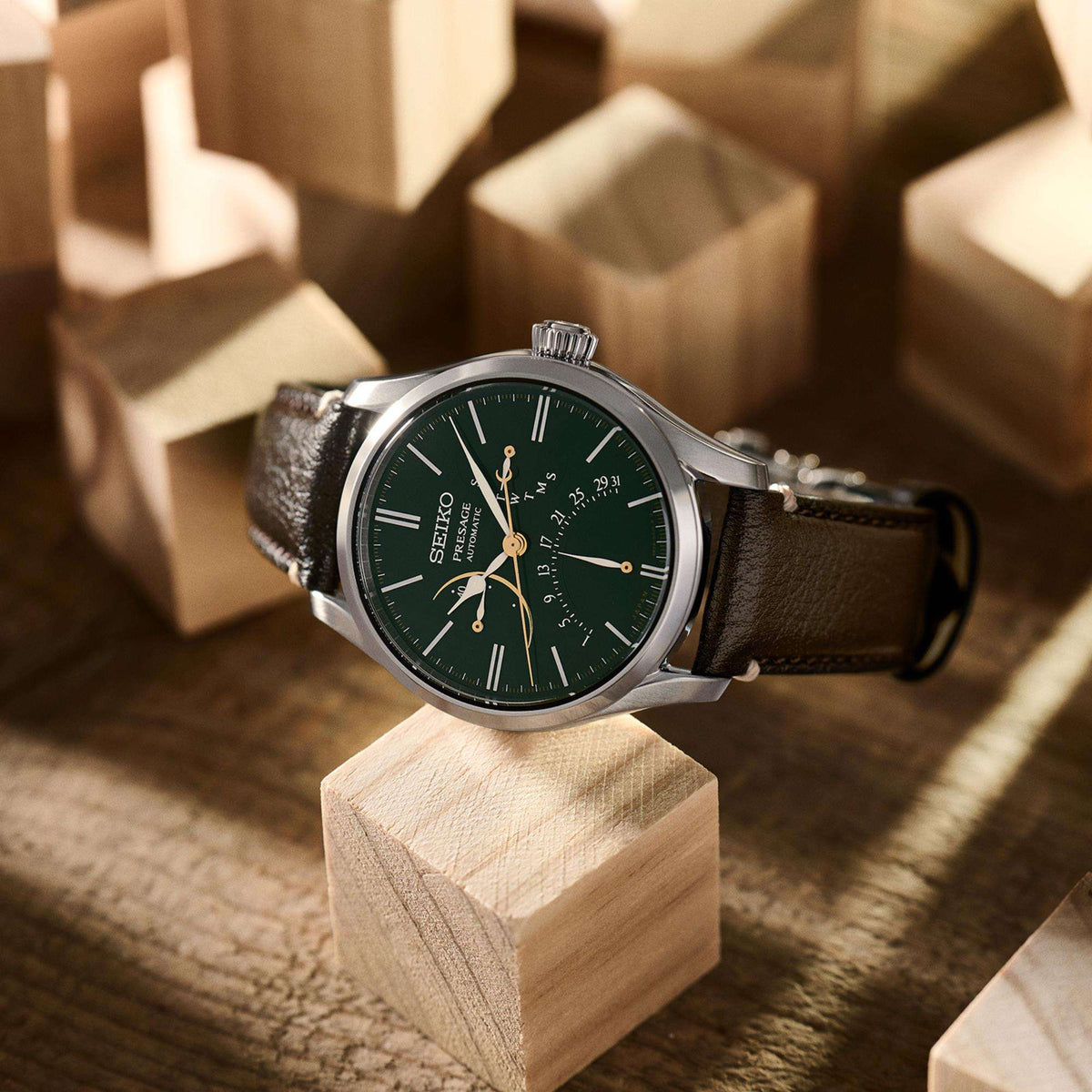 Men's automatic watch 3/4 view with green dial and black leather strap, silver case