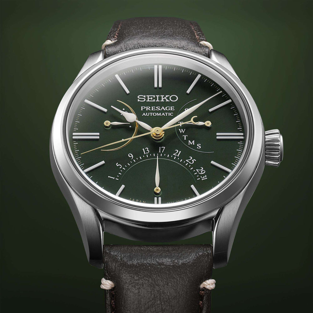 Men's automatic watch close-up with green dial, gold accents, and black leather strap