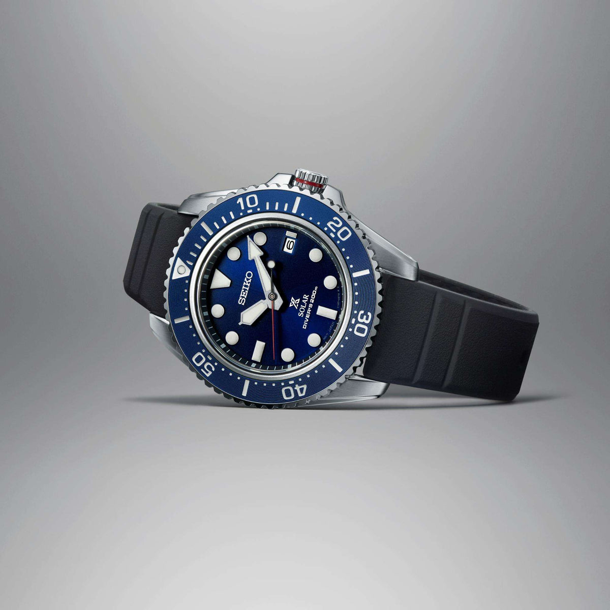Men's solar diver watch side view with blue dial, steel case, black rubber strap