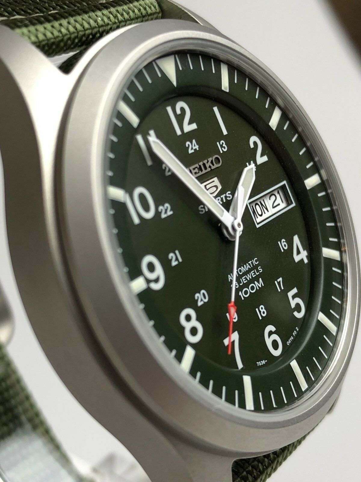Men's green dial automatic watch close-up with day-date window and silver case