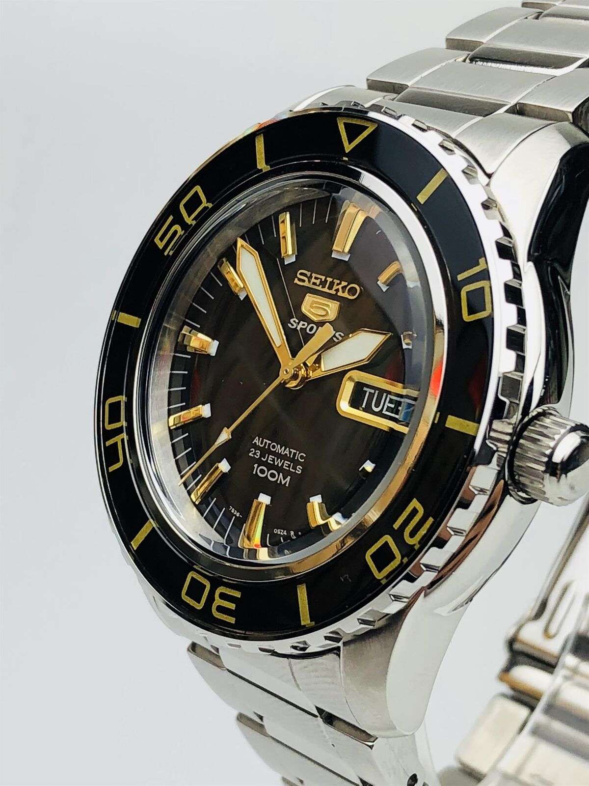Men's stainless steel automatic watch angled view, black dial with gold hands and date window