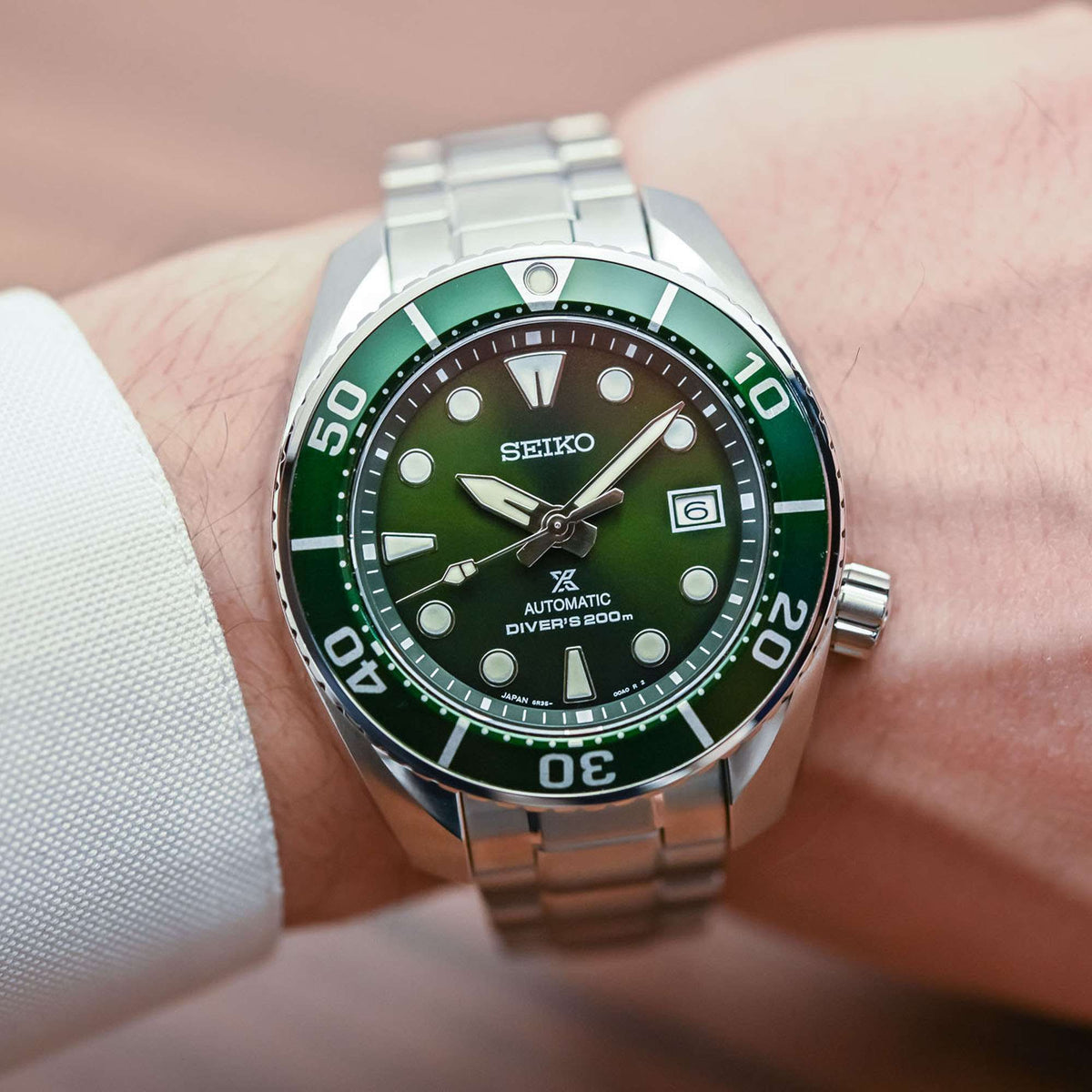 Men's diver watch on wrist: green dial, stainless steel bracelet, 200m bezel