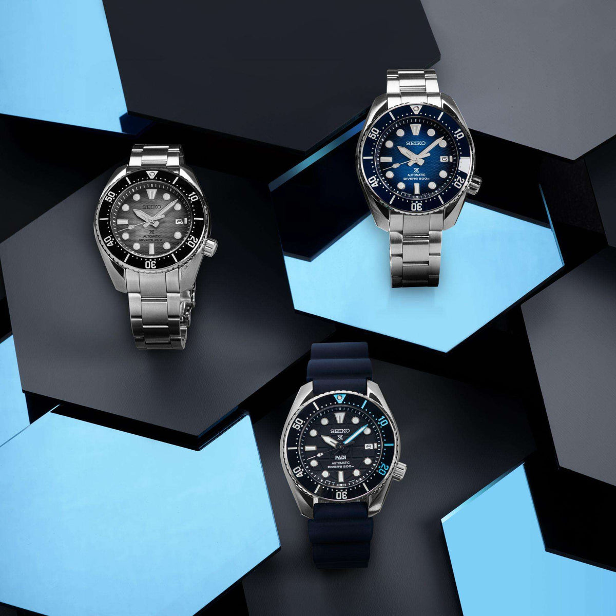 Three Seiko diver watches with steel cases, black dials, and blue silicone straps