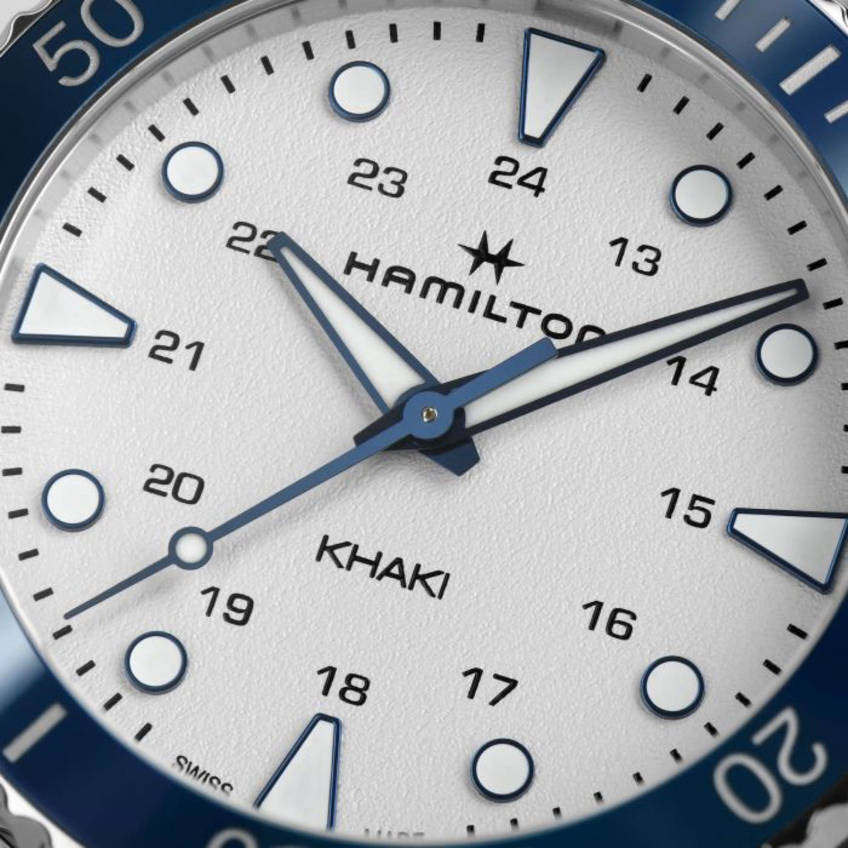 Hamilton Khaki watch dial close-up with white face, blue hands, and minute markers.