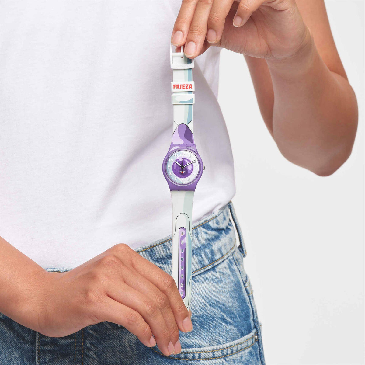 Person wearing a purple dial wristwatch with white strap and a light blue denim waistband.