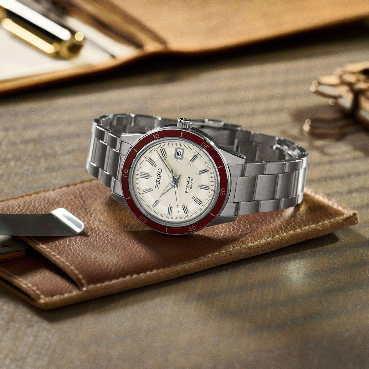 Stainless steel automatic wristwatch with white dial and red bezel, steel bracelet