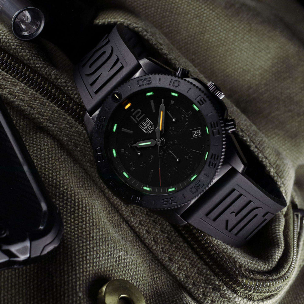 Black diver chronograph watch with luminescent green indices and date at 31