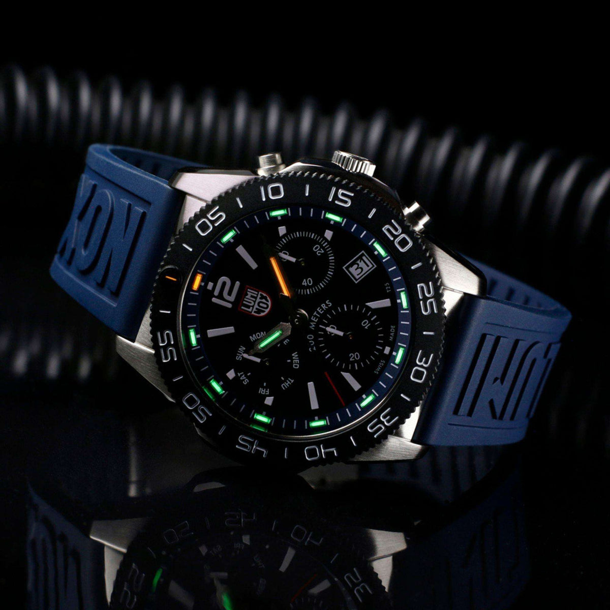 Black chronograph diver watch with blue rubber strap and luminous green dial accents