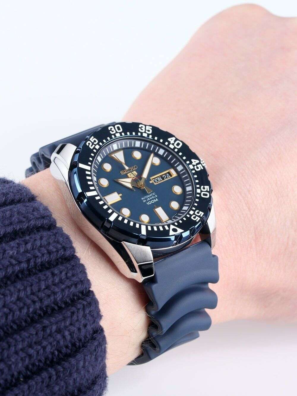 Men's Seiko 5 Sports automatic watch on wrist with blue dial, bezel, and blue silicone strap