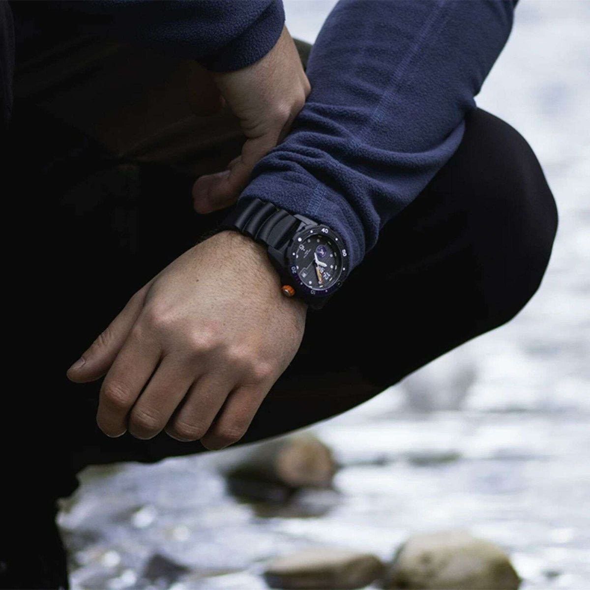 Men's wristwatch with black rubber strap and dark dial worn outdoors