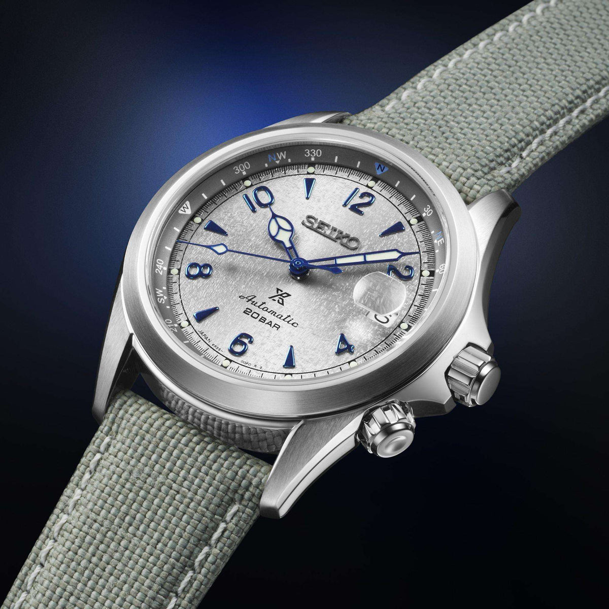 Men's stainless steel watch close-up with grey dial, blue accents, grey fabric strap