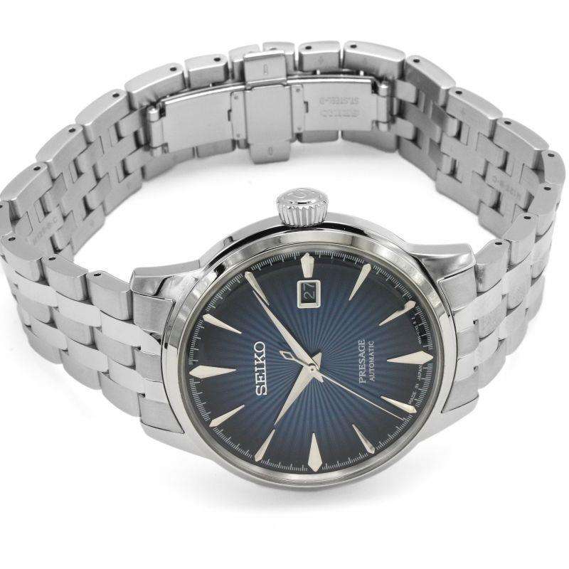 Silver stainless watch bracelet with blue dial and date window at 2 o'clock