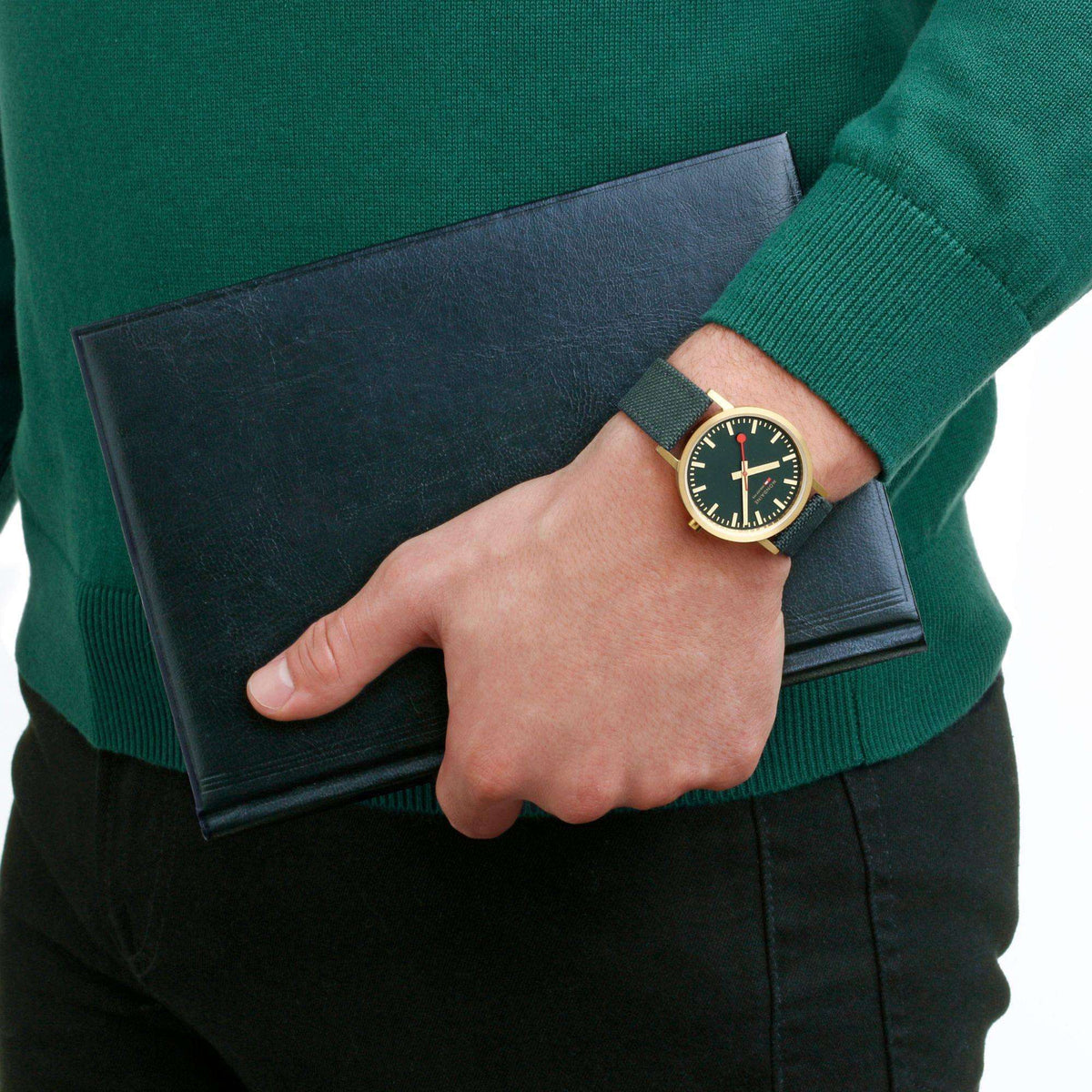 Forest green dial wrist watch on hand with gold-tone case and dark green fabric strap