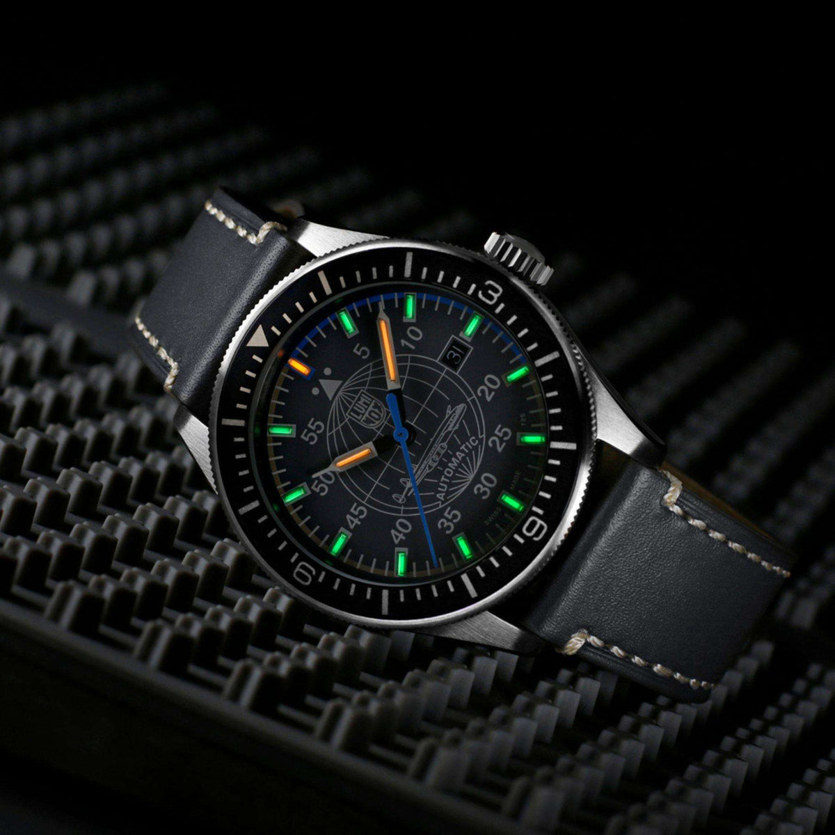 Luminox Constellation XA.9602 angled low light view displaying illuminated gas tubes against grey dial and leather strap