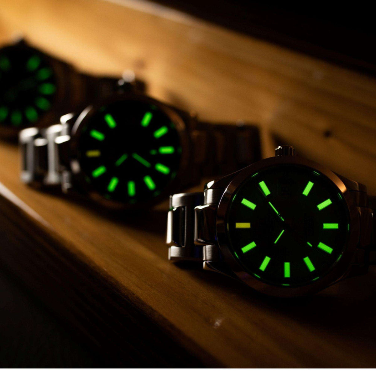 Men's wrist watch in stainless steel with dark green dial and luminous raised markers.